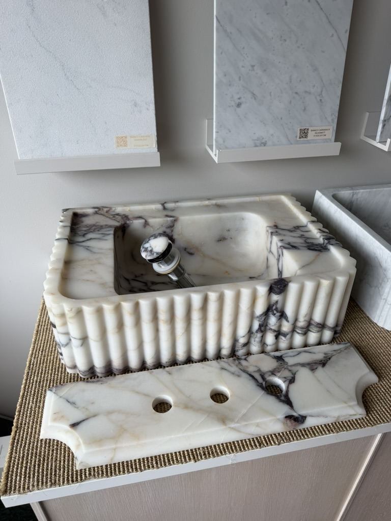 Håndlaget servant i eksklusiv Calacatta Viola-marmor med elegante riller, sluk i matchende sten og profilert backsplash.
