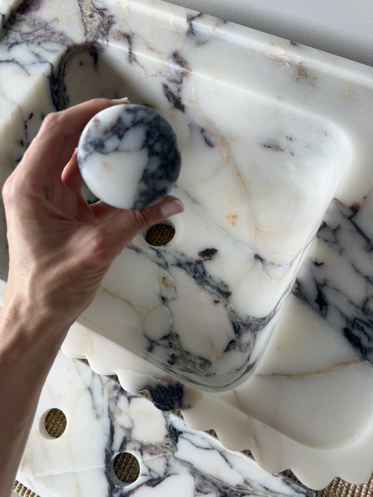 Håndlaget servant i eksklusiv Calacatta Viola-marmor med elegante riller, sluk i matchende sten og profilert backsplash.